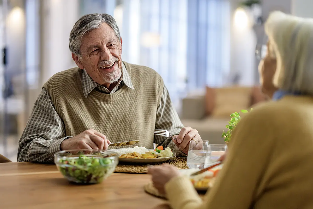 A senior couple laughing together over dinner
